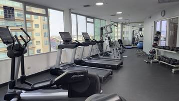 Un gimnasio con cintas de correr, elípticas y equipo de pesas.