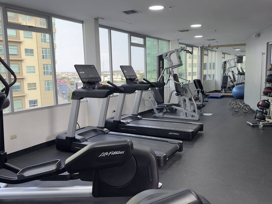 Un gimnasio con cintas de correr, elípticas y equipo de pesas.