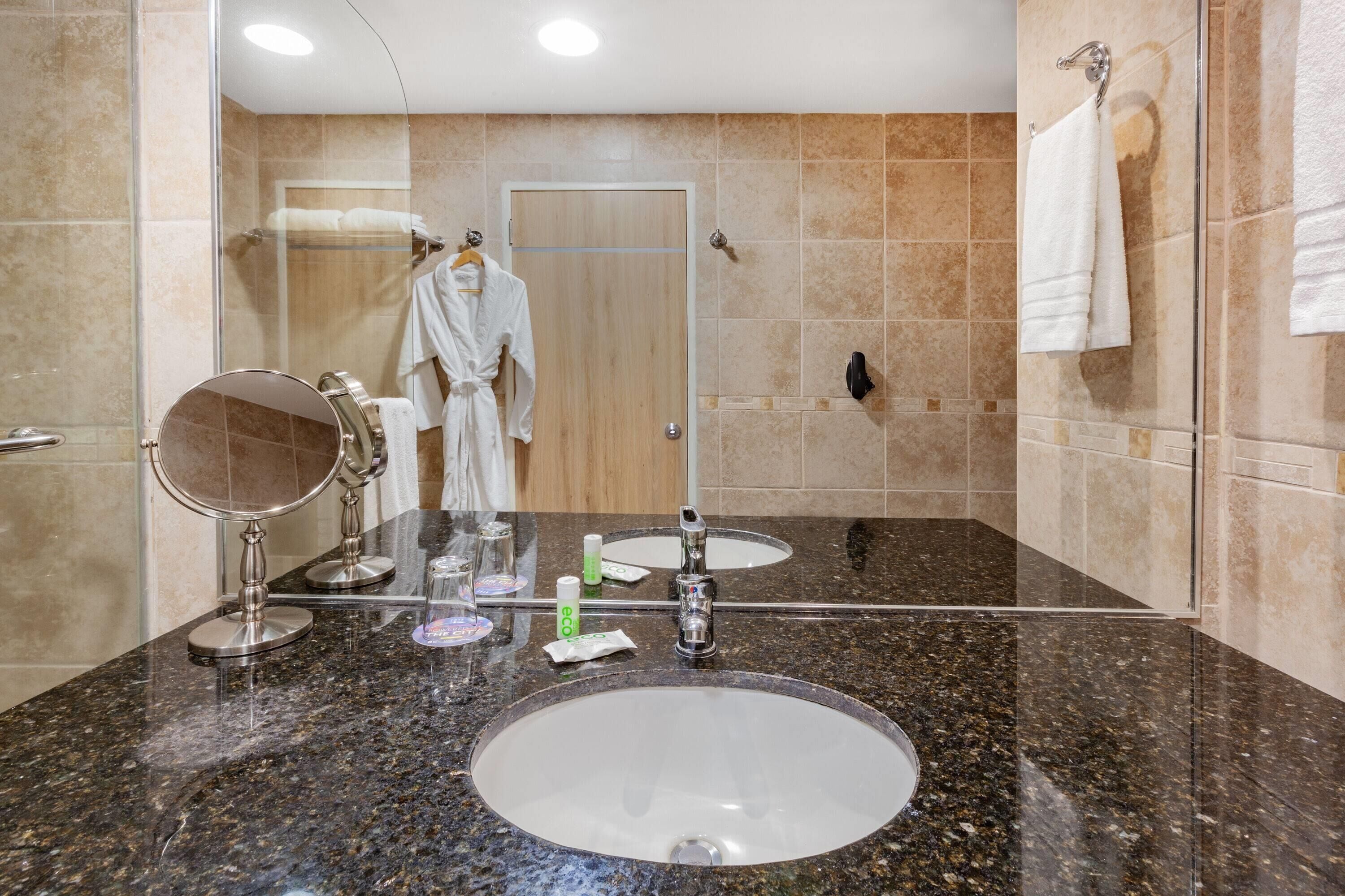 A bathroom with two sinks, a mirror, and a robe rack.