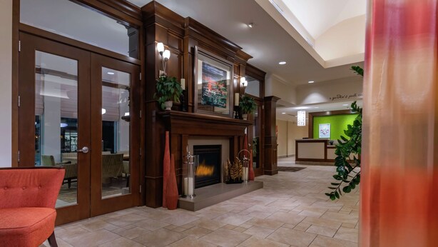 A spacious lobby with a fireplace, a red armchair, and a reception desk.