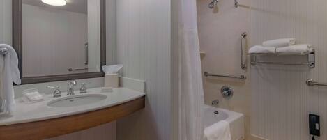 A bathroom with a double sink, a mirror, a shower with a glass door, a bathtub, and a towel rack.