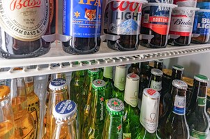 Mostrador refrigerado con diversas botellas de cerveza, incluyendo marcas como Bass, IPA, Coors Light y Budweiser.