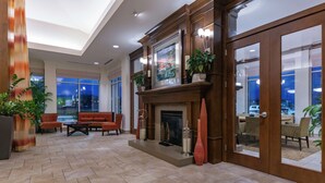 A spacious lobby with a fireplace, comfortable seating, and large windows.