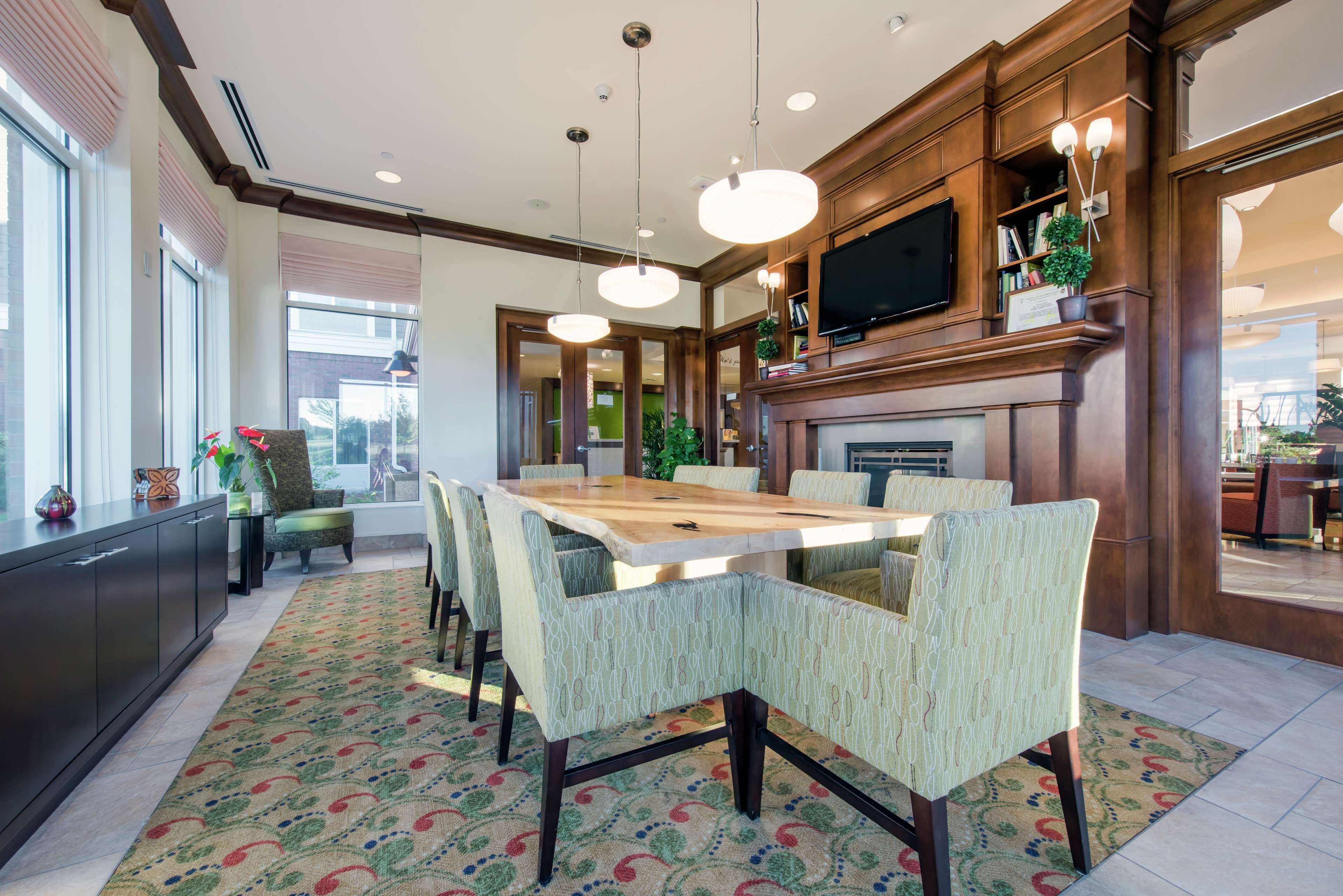 A modern kitchen with a large wooden table, patterned chairs, and pendant lighting.