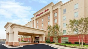 A Hampton Inn hotel with a brick facade, a covered entrance, and a clear sky.