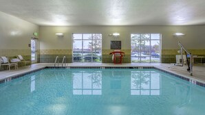 A swimming pool with clear water, a lifeguard chair, and a sign indicating the pool's depth.