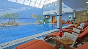 An indoor swimming pool with a tropical mural, lounge chairs, and a bar area. - Ayla Hotel  (Al Ain)