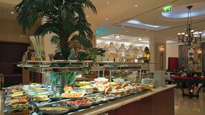 A buffet area with various food items and a large potted plant. - Ayla Hotel  (Al Ain)