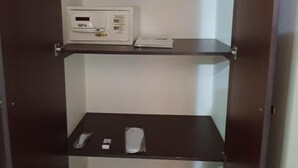 A room with a built-in microwave on the upper shelf and a remote control and a small item on the lower shelf. - Ivory Hotel Apartments (Abu Dhabi)