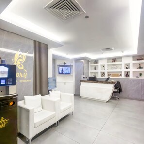 A modern reception area with a white desk, seating, and a water dispenser.