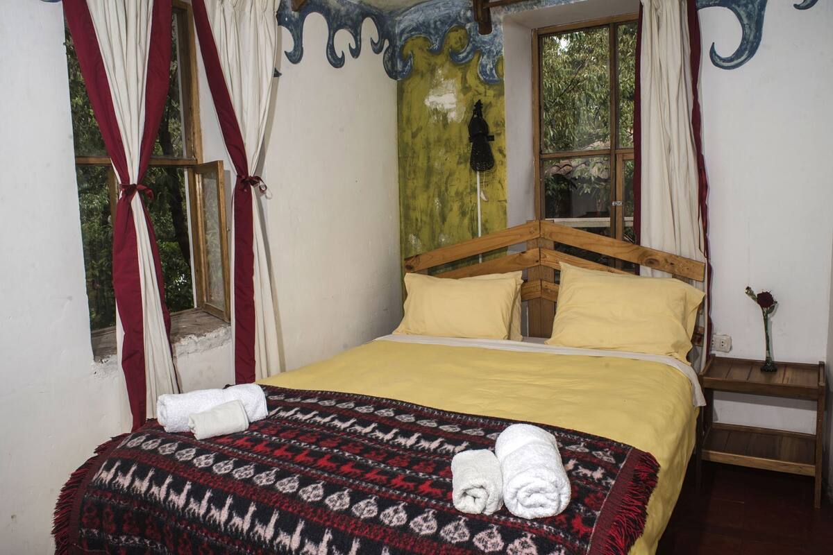 A bed with a wooden headboard, a yellow bedspread, and a patterned blanket.