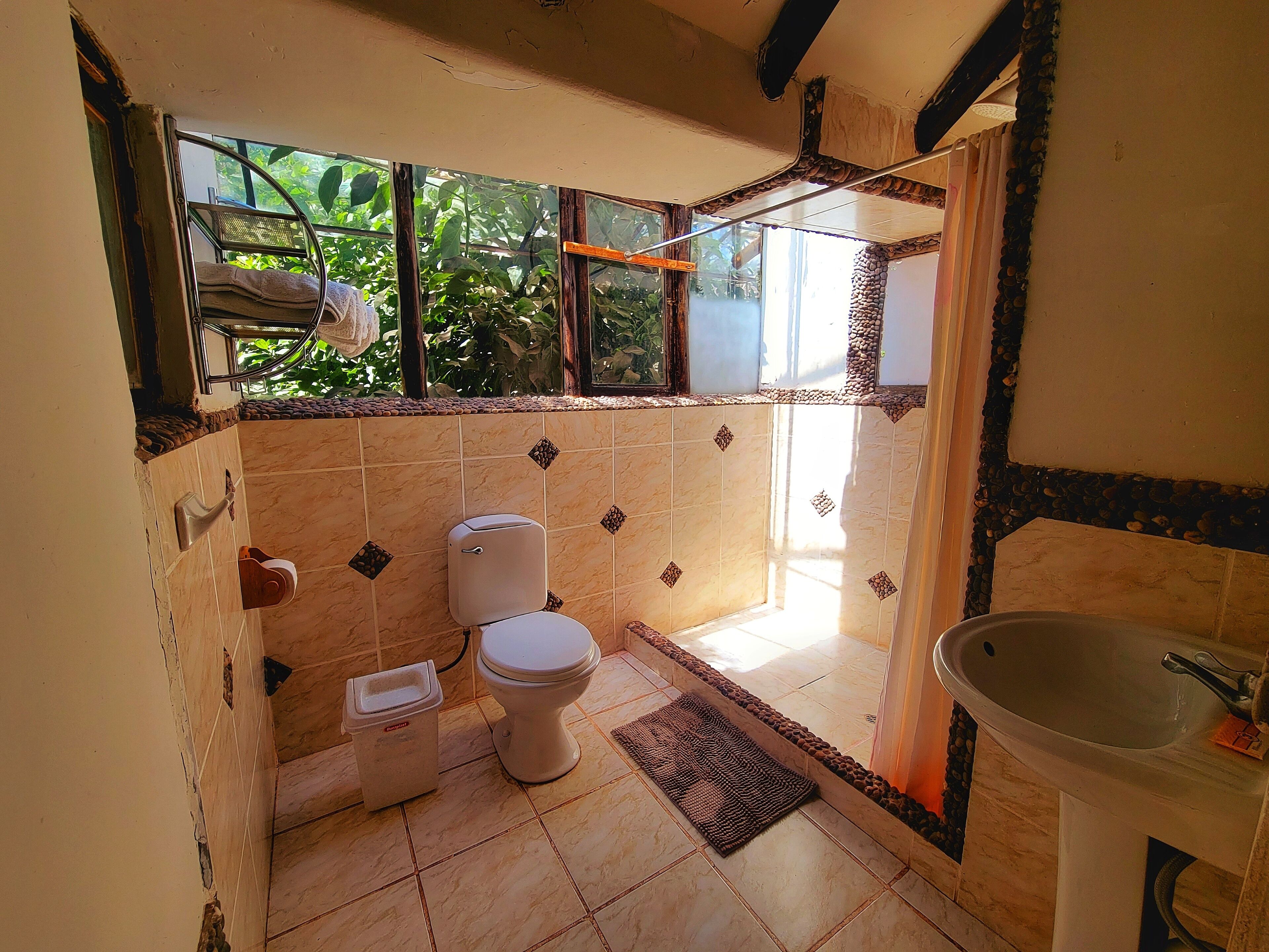 A bathroom with a toilet, sink, and window.