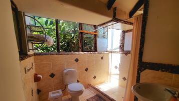 A bathroom with a toilet, sink, and window.