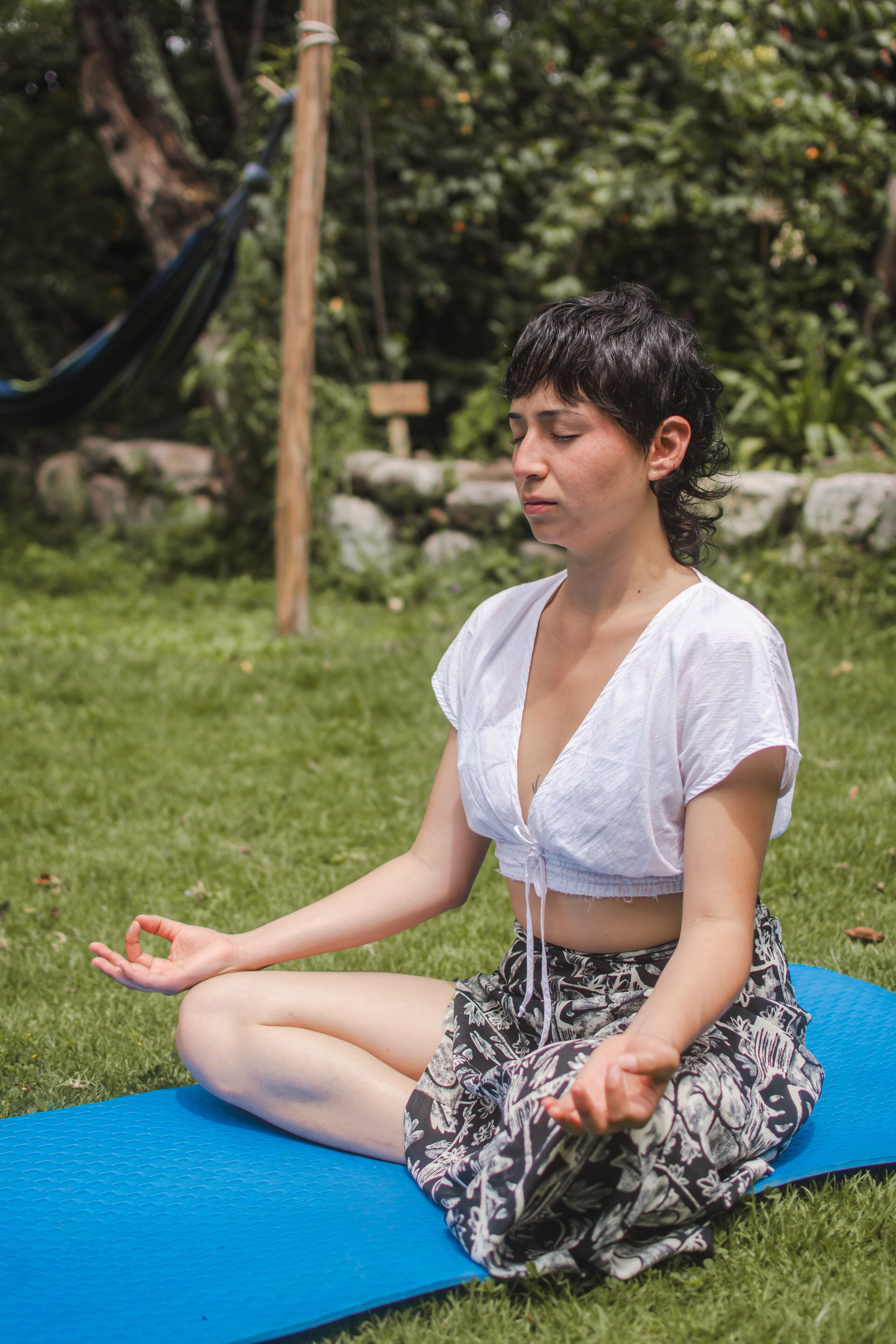 A person sitting on a blue exercise mat outdoors.