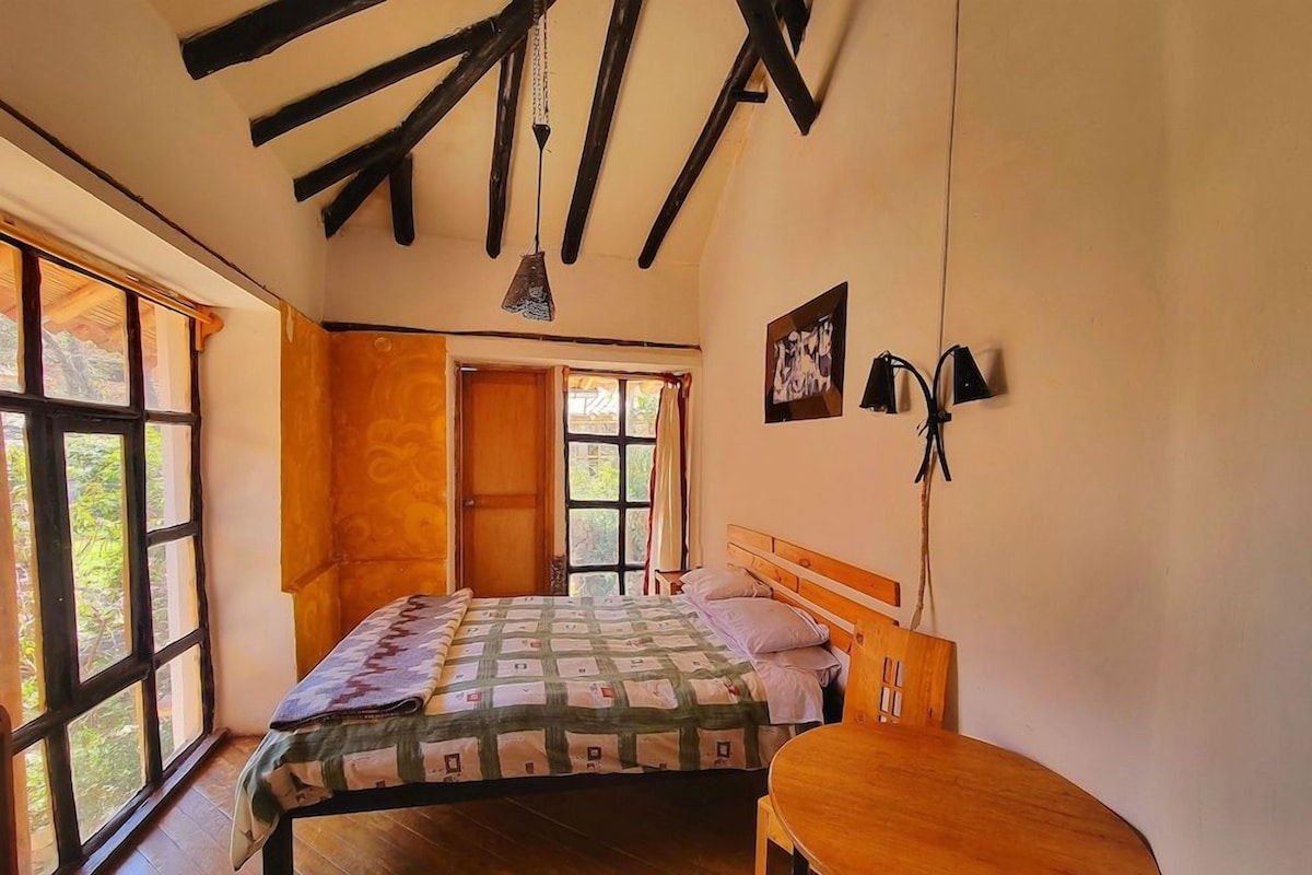 A bedroom with a bed, a wooden table, and a window.