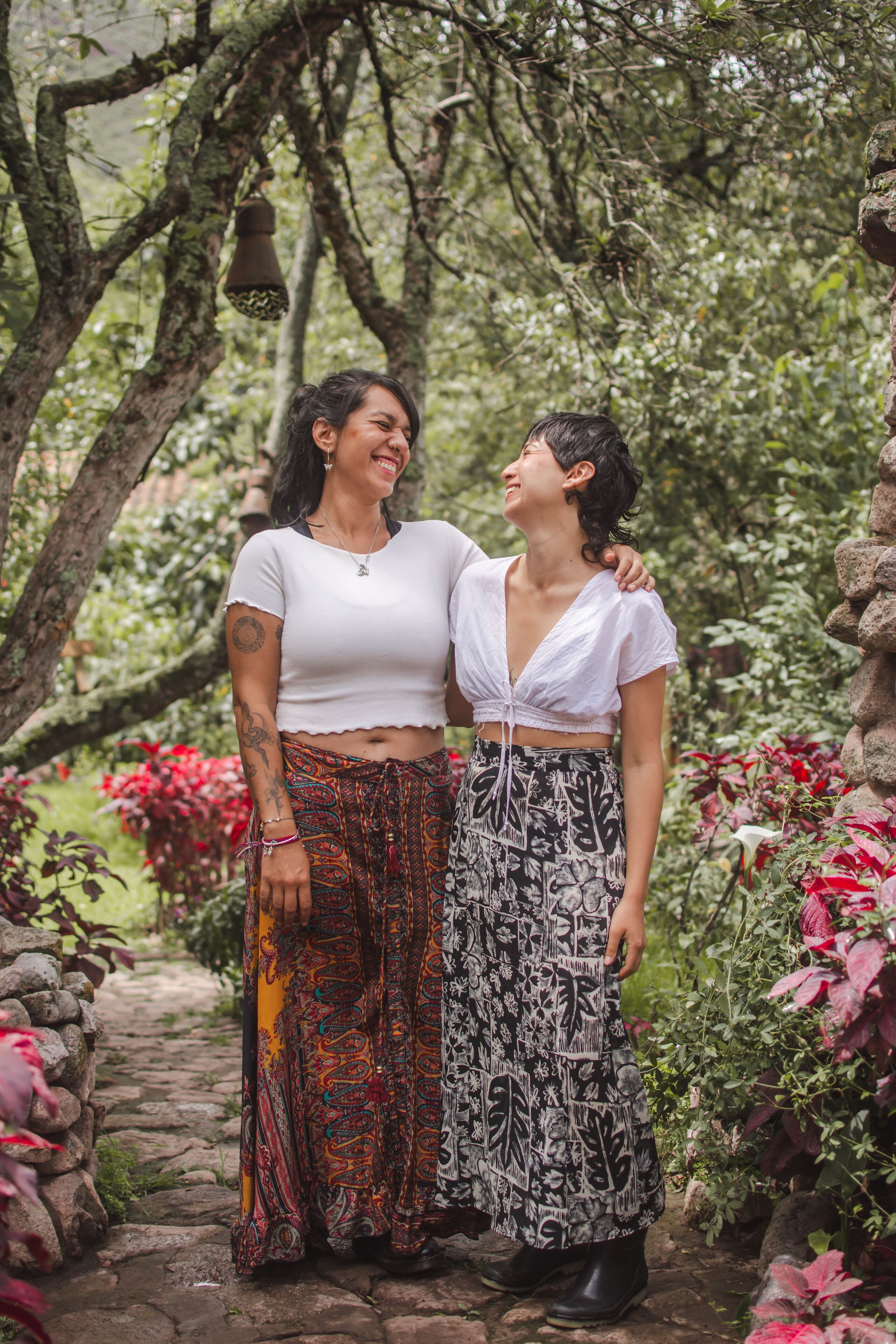 Two people standing in a garden with stone pathways and lush greenery.