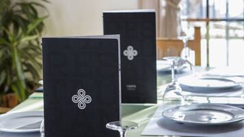 Une table dressée pour le repas, avec un menu, un verre à vin et une plante en pot.