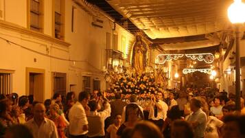 A crowded street scene with a large group of people gathered around a central display, possibly a religious or cultural event.