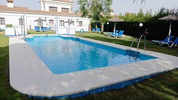 Una piscina al aire libre de temporada, sombrillas, tumbonas