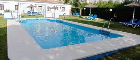 Piscina a l'aire lliure de temporada, para-sols i gandules
