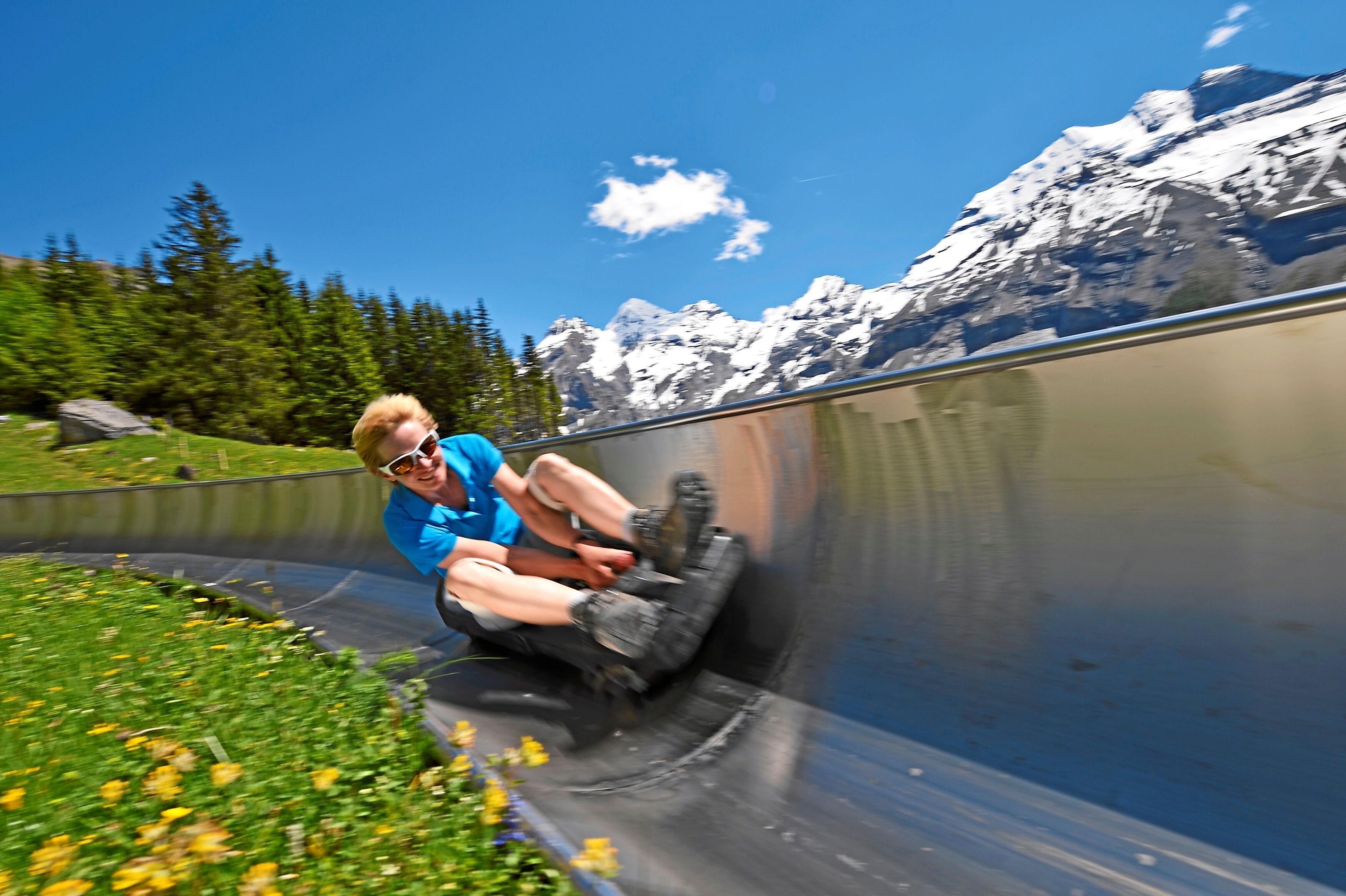 A person sliding down a water slide with a mountainous landscape in the background.
