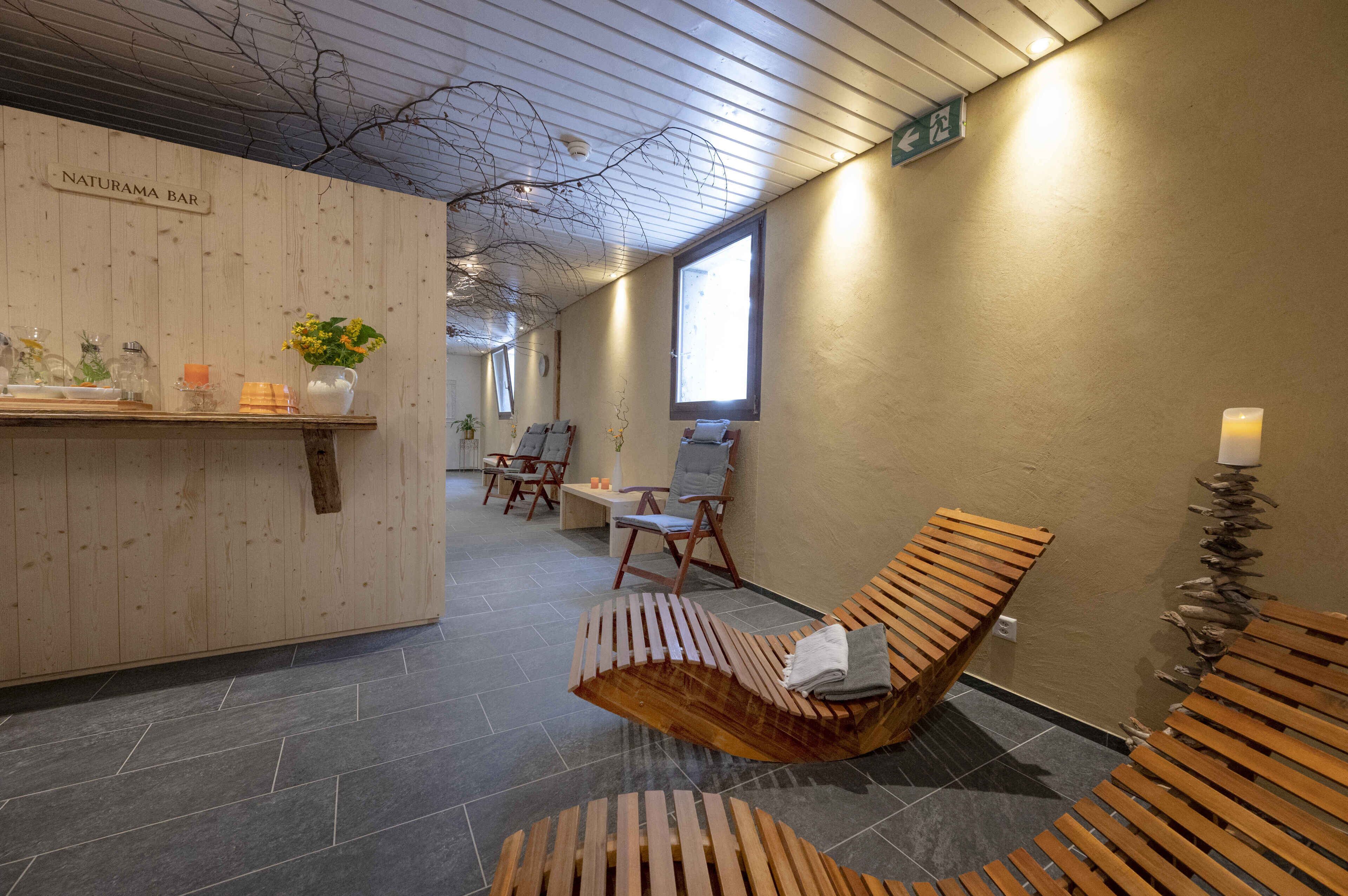 A wooden reception desk with a sign reading "NATURAMA BAR," wooden lounge chairs, and a tiled floor.