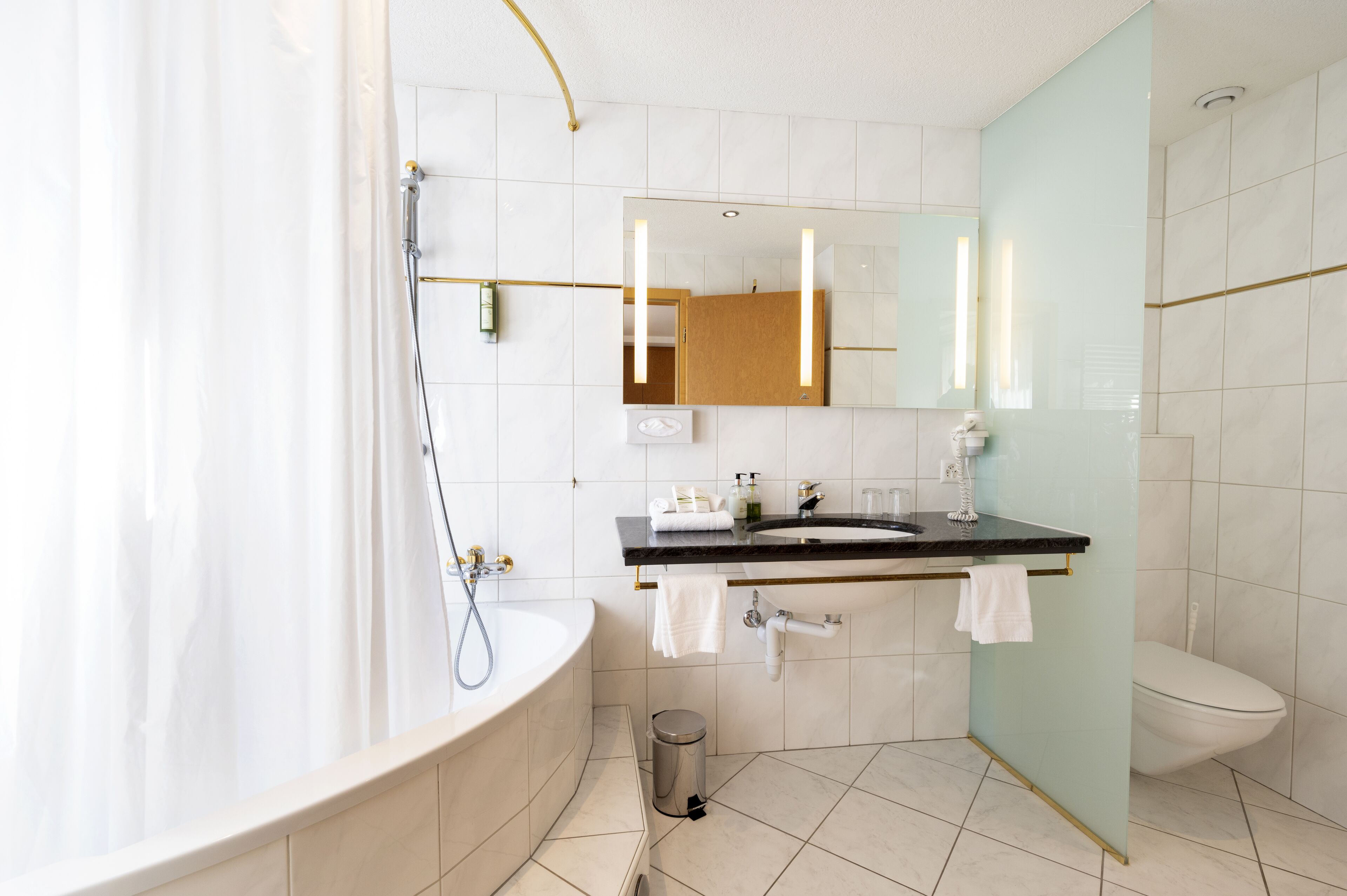 Un baño moderno con bañera, cabina de ducha de vidrio, lavamanos con espejo e inodoro.