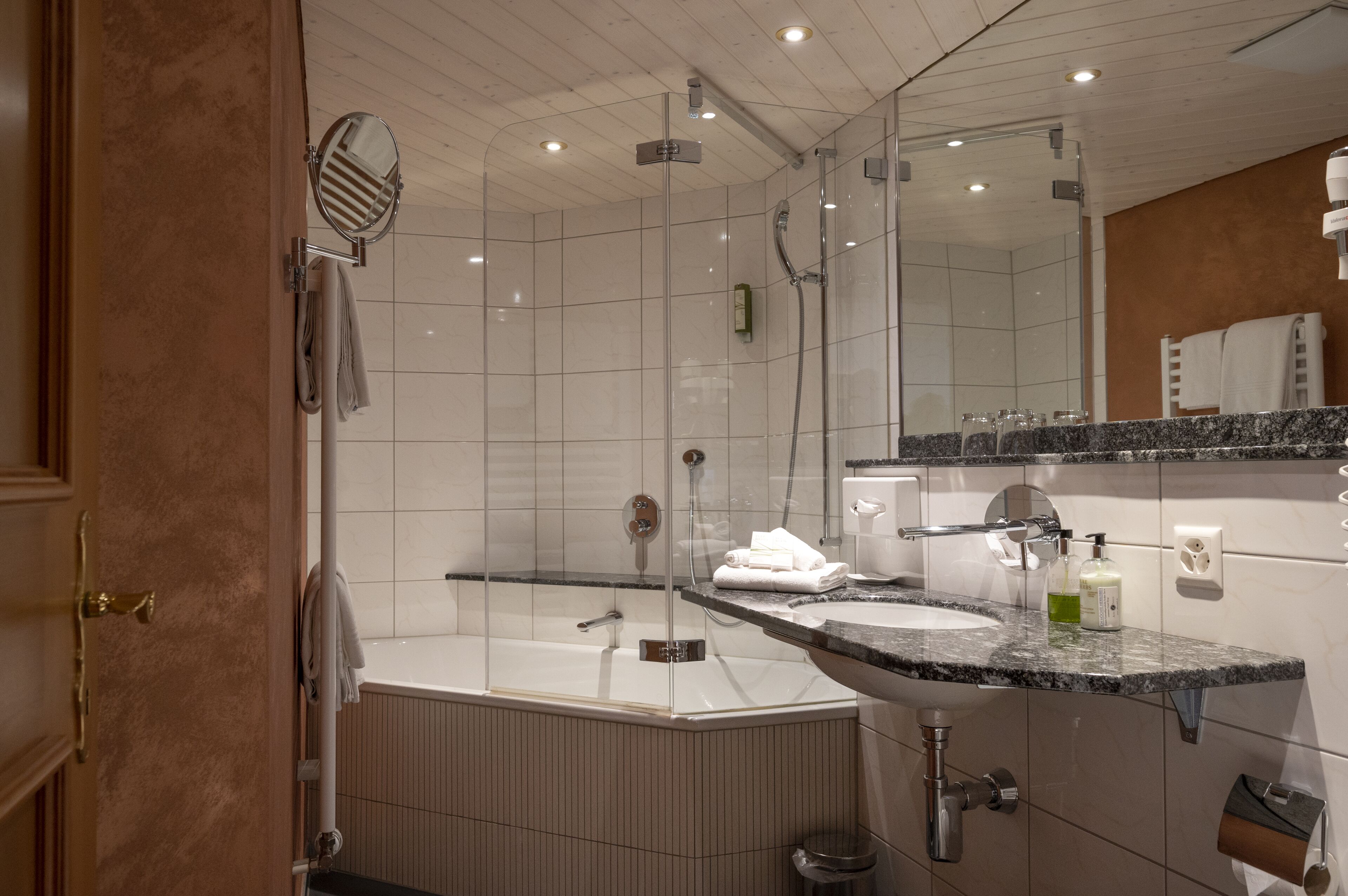 Ein modernes Badezimmer mit einer begehbaren Glasdusche, einer freistehenden Badewanne und einem Waschbecken mit Granitplatte.