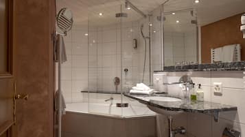 Ein modernes Badezimmer mit einer begehbaren Glasdusche, einer freistehenden Badewanne und einem Waschbecken mit Granitplatte.