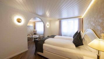 A hotel room with a large bed, a chair, a desk, and a lamp.