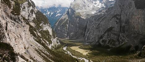 Un paisaje montañoso con un río que serpentea por un valle, rodeado de acantilados escarpados y densos bosques.