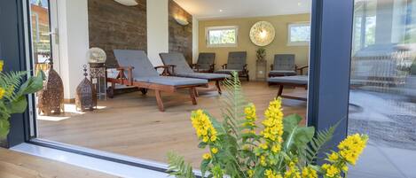 A modern interior with wooden floors, a large window, and multiple lounge chairs.