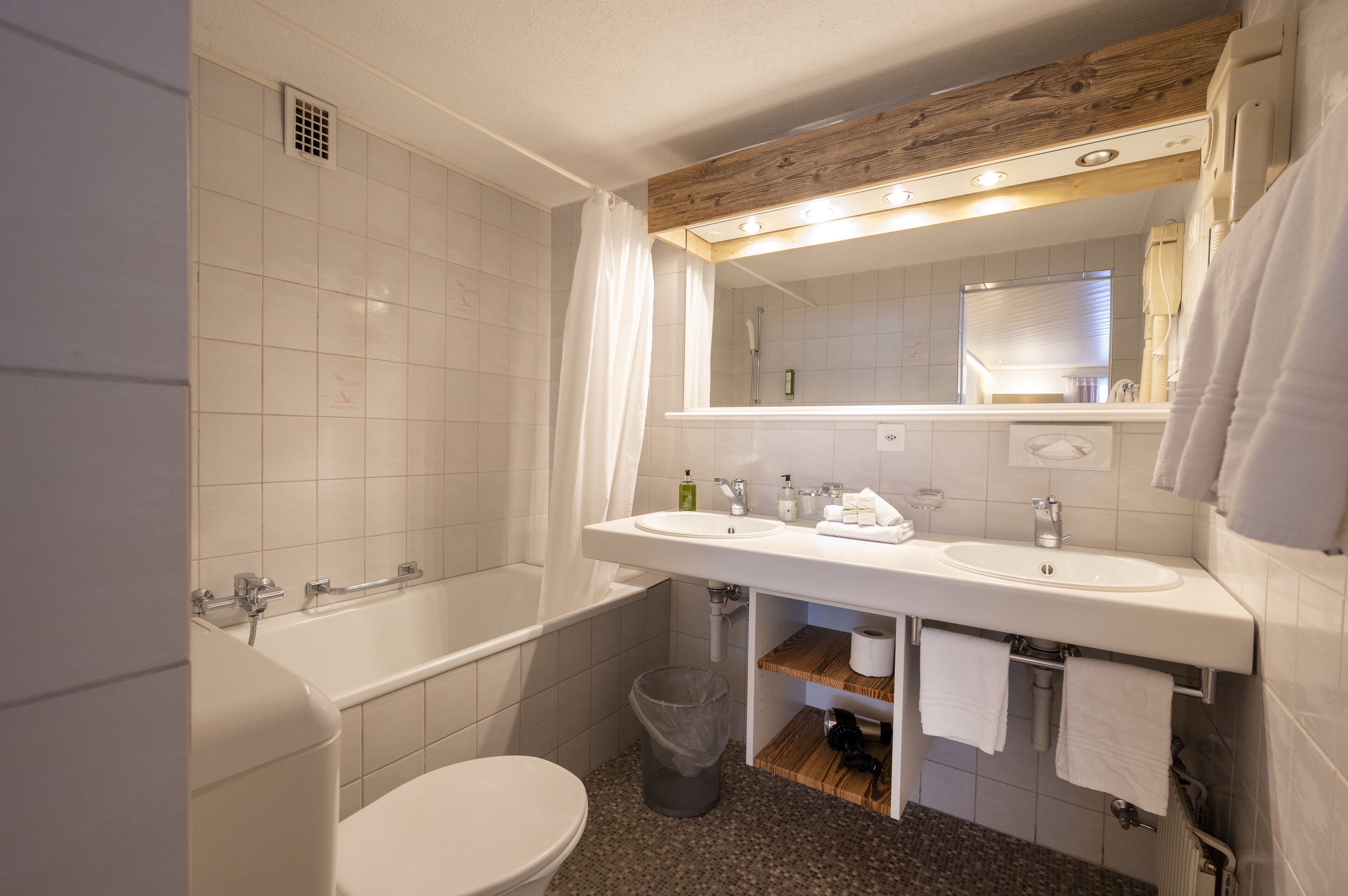 A modern bathroom with a white sink, mirror, and bathtub.