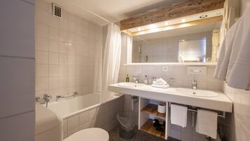 A modern bathroom with a white sink, mirror, and bathtub.