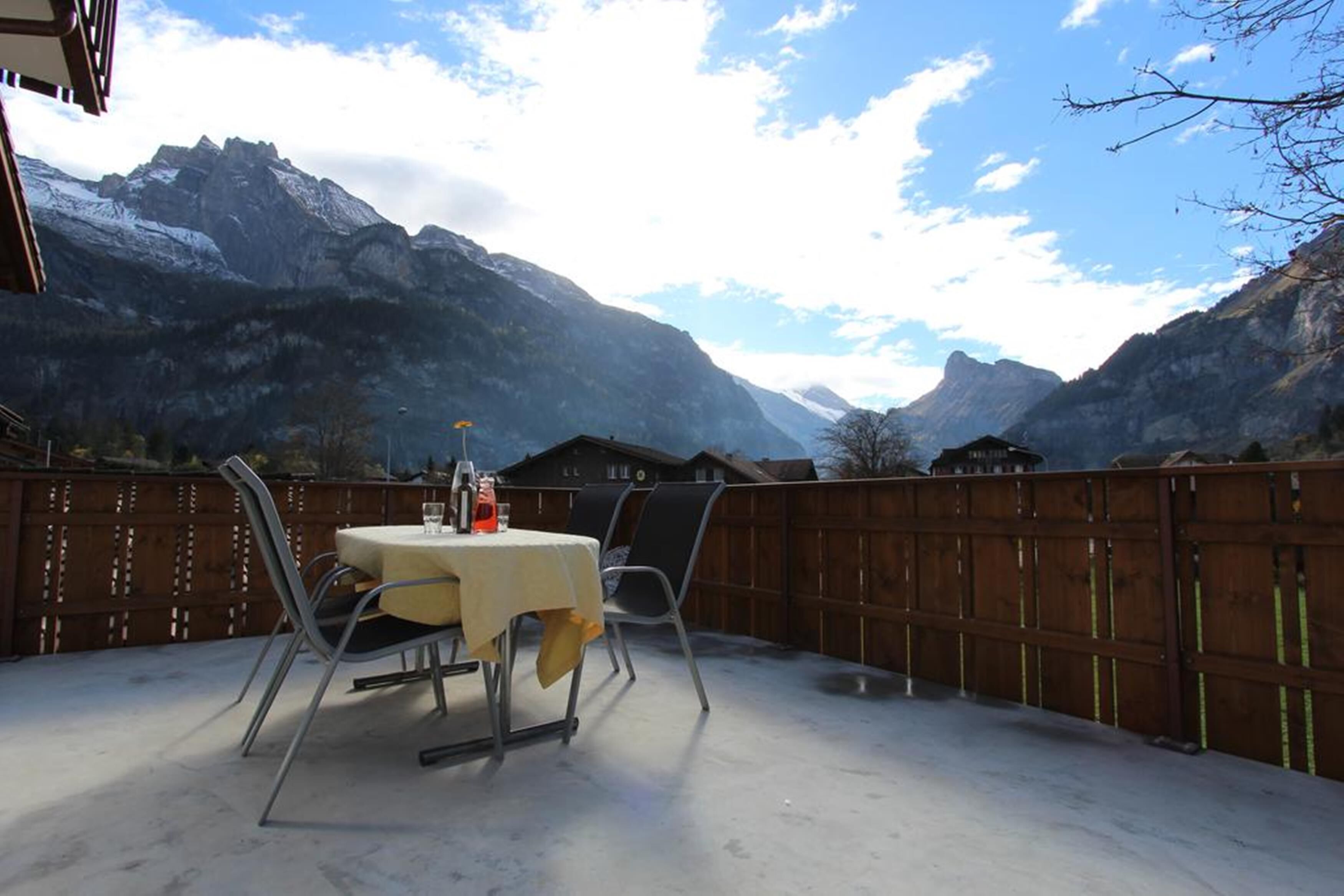 Un patio con tavolo e sedie, affacciato su un paesaggio montuoso.