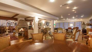 Amplia sala de estar con una gran mesa de comedor de madera, asientos cómodos, chimenea y techo bien iluminado.