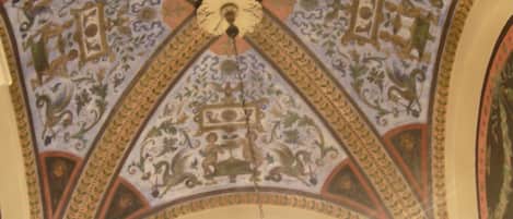 Un plafond orné de motifs complexes et un lustre.