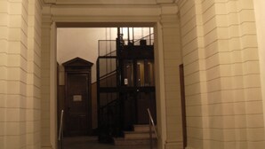 A grand staircase with a chandelier, leading to a dark staircase. - Alla Stazione (Trieste)