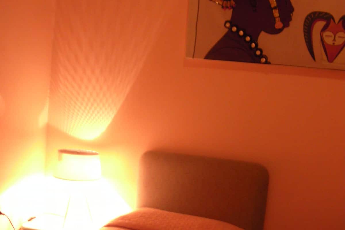 A room with a bed, a lamp, and a wall decoration.