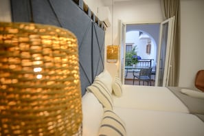 Un dormitorio con cama, lámpara de noche y vistas a un balcón con mesa y sillas.