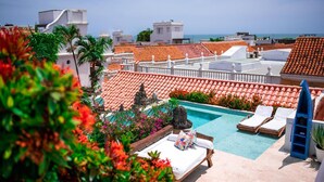 A rooftop pool with lounge chairs and a view of the sea.
