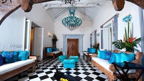 A room with a checkered floor, wooden furniture, a chandelier, and a fireplace.