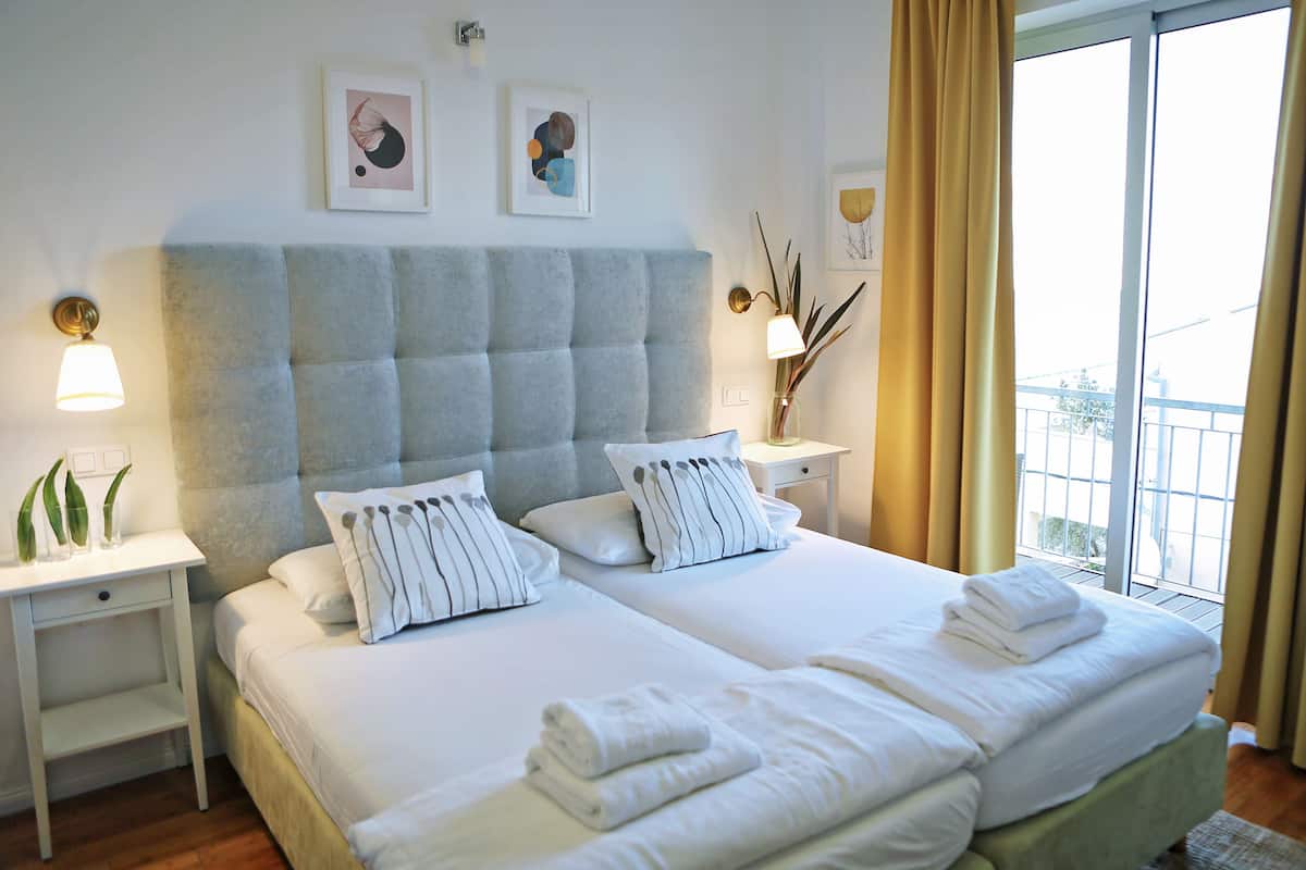 Ein Hotelzimmer mit einem großen Bett, zwei Nachttischen und einem Fenster mit Vorhängen.