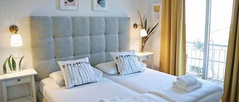 Une chambre d’hôtel avec un grand lit, deux tables de chevet, une commode et une fenêtre avec des rideaux.