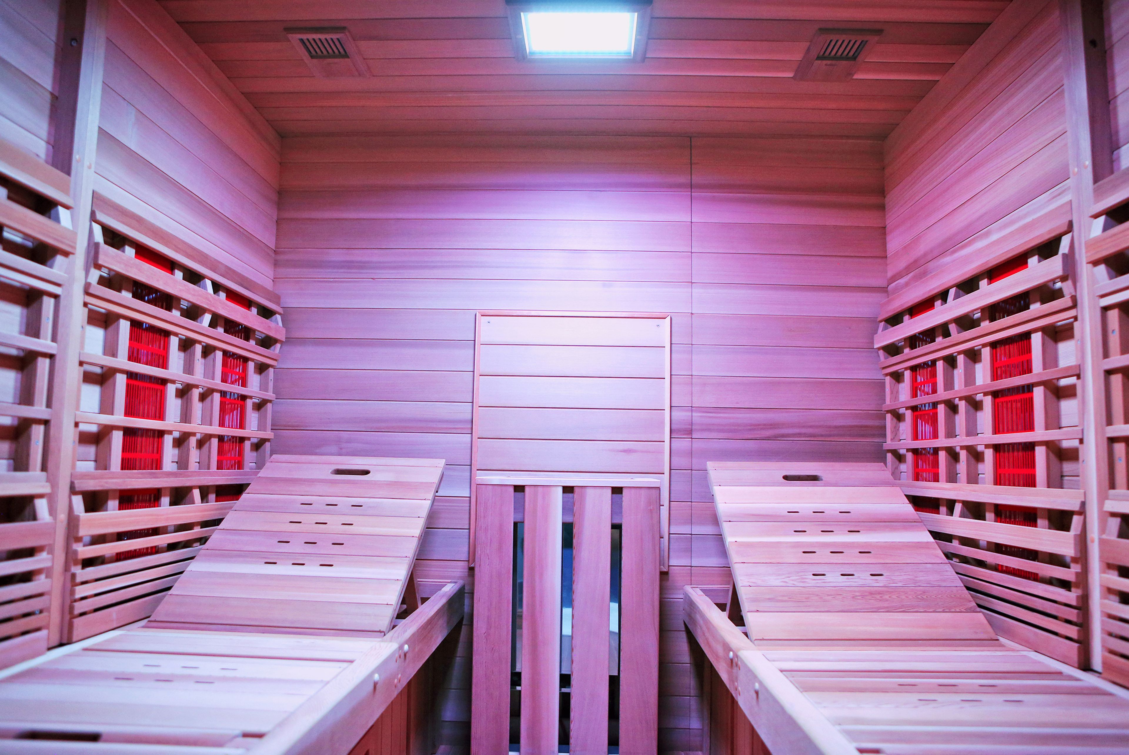 Een sauna met houten banken en rode opbergbakken.