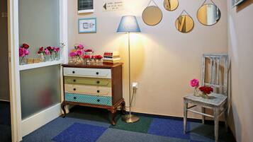Un couloir avec une commode de style vintage, une lampe et une chaise agrémentée de fleurs.