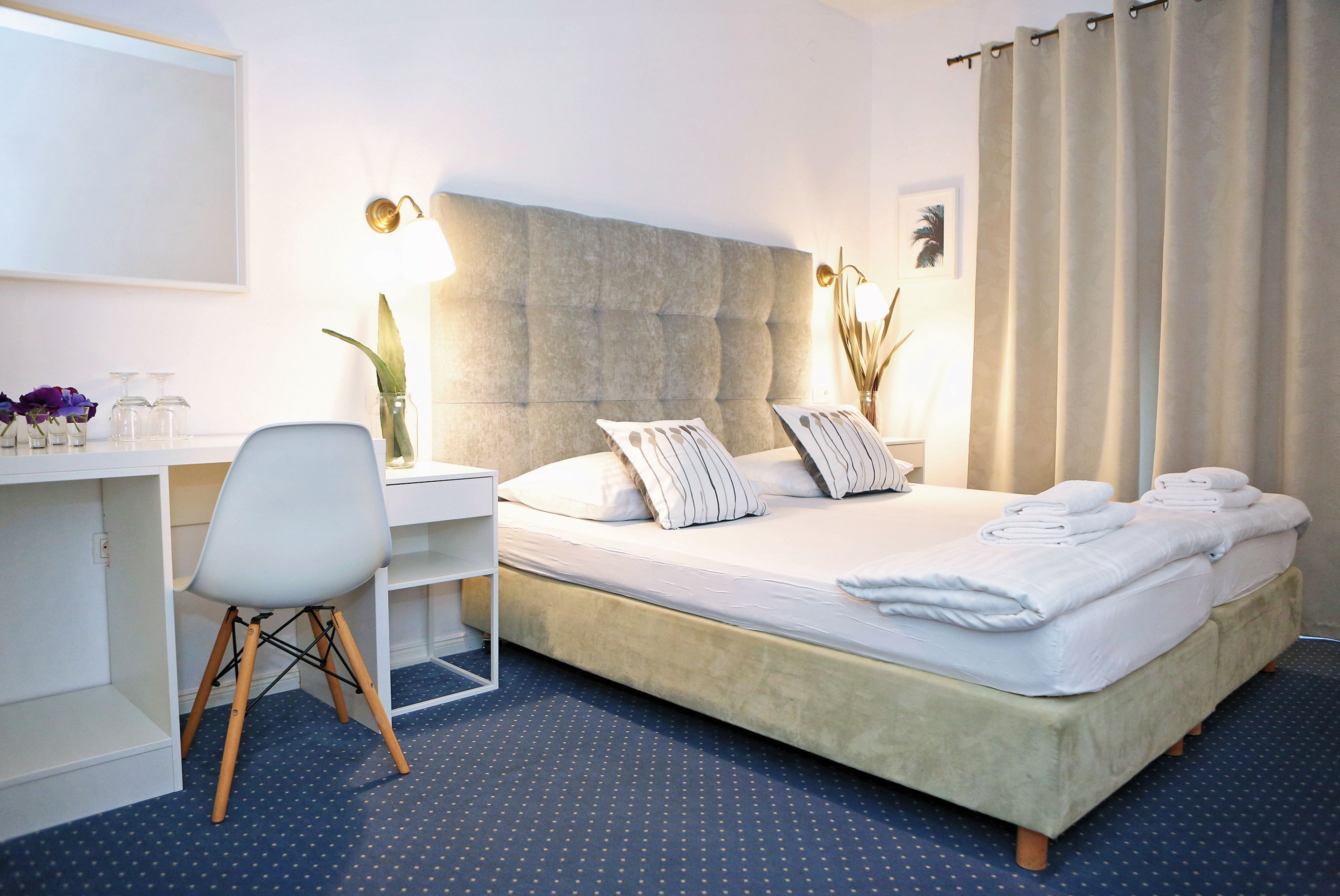 A hotel room with a bed, a desk, a chair, and a large window with curtains.