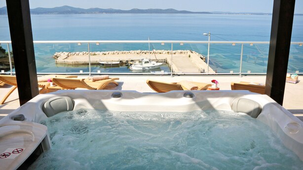A hot tub with a view of the sea and a dock with boats. - Hotel Delfin (Zadar)