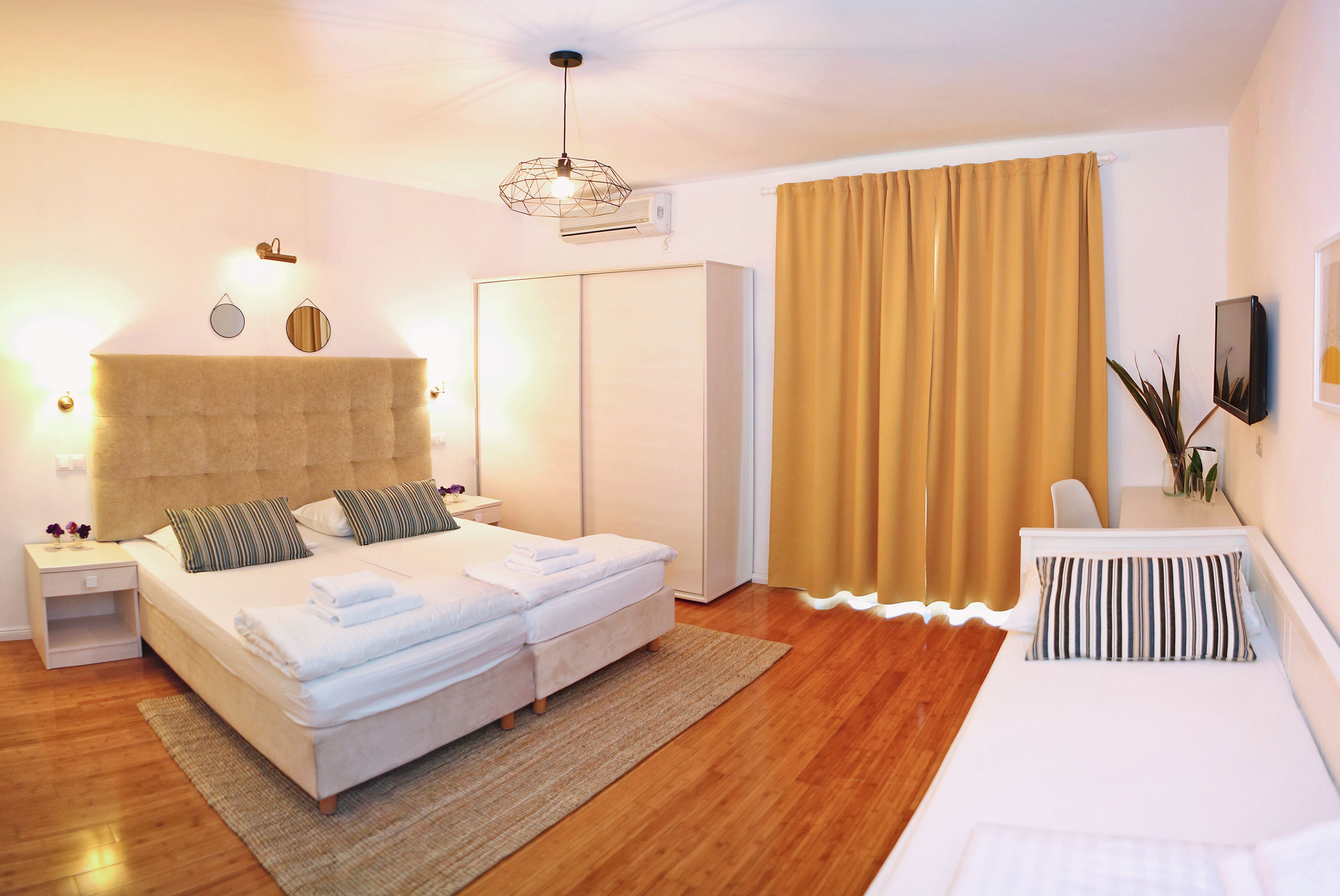 A modern bedroom with a large bed, a bedside table, a wardrobe, and a view of the outdoors.