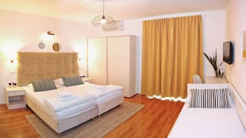 A modern bedroom with a large bed, a bedside table, a wardrobe, and a view of the outdoors.